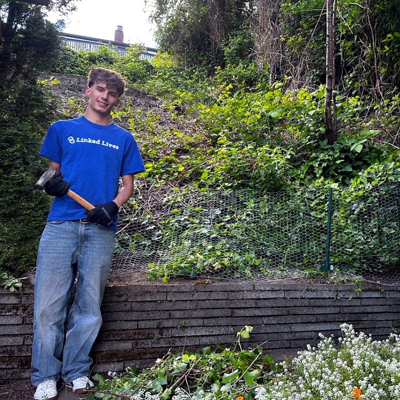 Linked Lives helper clearing overgrowth in a yard