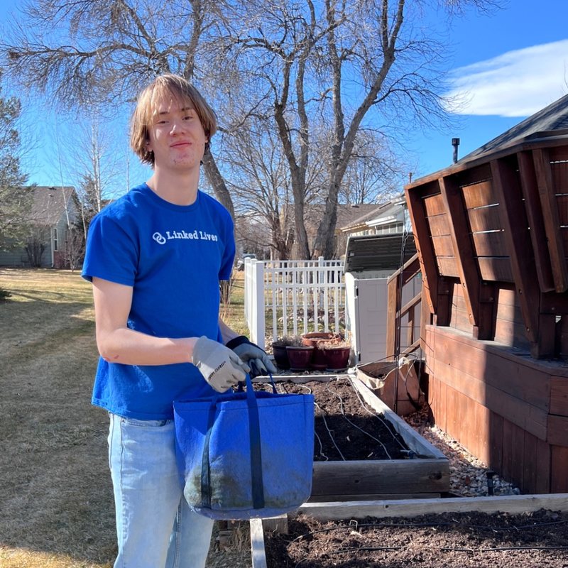 Linked Lives helper carrying a yard debris bin